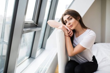 Büyük pencere ve kamera göz yakın yatak ucunda oturan kadın