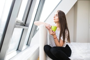 Genç kadın yatakta kahve içmek ve sabah kafanı çevir