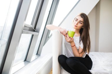 Genç kadın yatakta kahve içmek ve sabah kafanı çevir