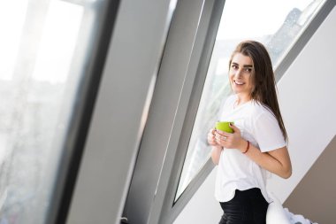 Güzel genç kadın kahve evin içinde belgili tanımlık pencere başına oturmuş içme.