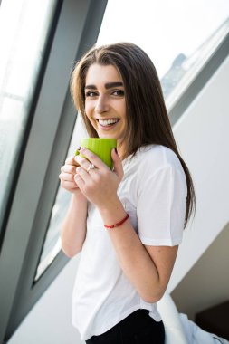Güzel genç kadın kahve evin içinde belgili tanımlık pencere başına oturmuş içme.