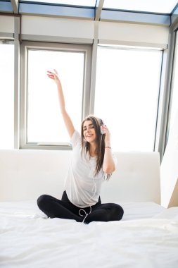 mutlu kadın veya smartphone müzik ve dans evde yatakta Kulaklığımda genç kız