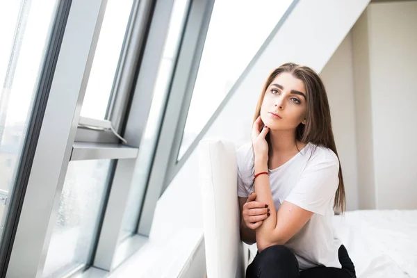 Woman sitting on the end of bed near big window and look at camera — Stock Photo, Image