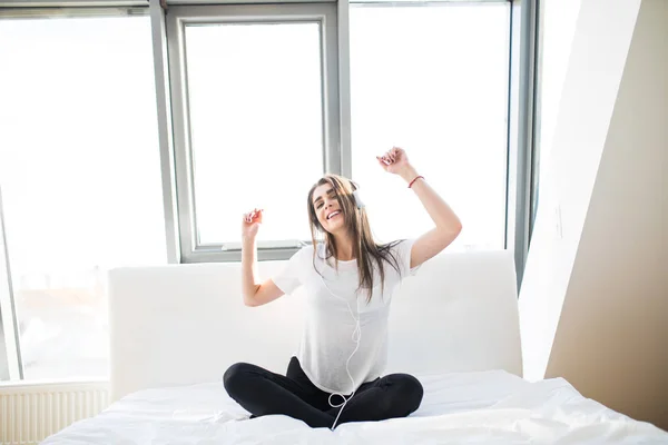 Boldog asszony vagy tizenéves lány fejhallgató hallgató-hoz zene-ból smartphone és tánc ágyban otthon — Stock Fotó