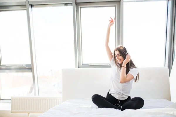 Boldog, fiatal nő, hallgató-hoz zene és énekelni az ágyban — Stock Fotó
