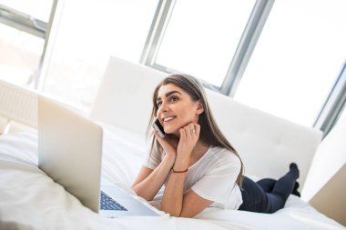 Gülümseyen kadın onu laptop önünde yatak aşağı yalan