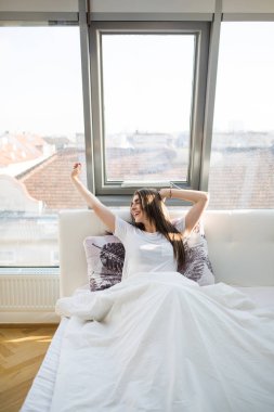 Yatakta sonra uyanmak kadar güneş ışığı ile sabah germe kadın arkadan görünüş