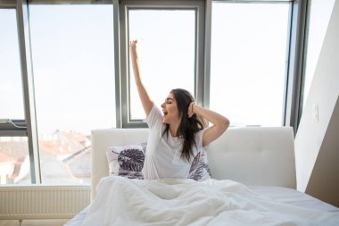 Kadın uyandıktan sonra yatakta geriniyor.