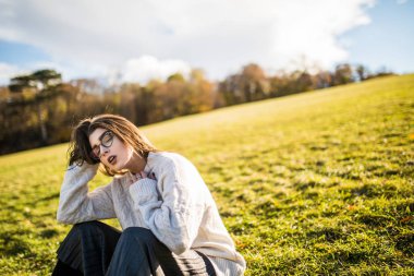 Güneşli günde Park çimenlerin üzerinde oturan kadın