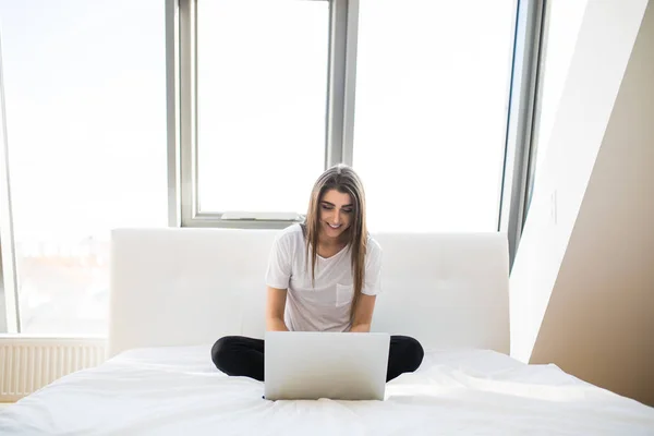 Mujer bonita usando su portátil en la cama por la mañana — Foto de Stock