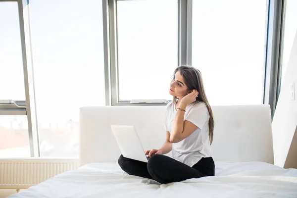 Kobieta w łóżku z laptopa na nogi — Zdjęcie stockowe