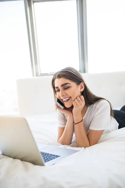 Uśmiechnięta kobieta, leżąc w łóżku przed jej laptop — Zdjęcie stockowe