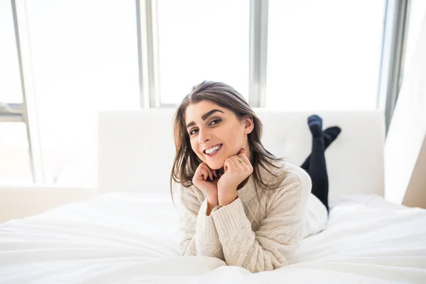 Schöne Frau auf weißem Bett liegend — Stockfoto