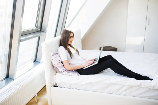 Jeune femme utilisant un ordinateur portable au lit — Photo