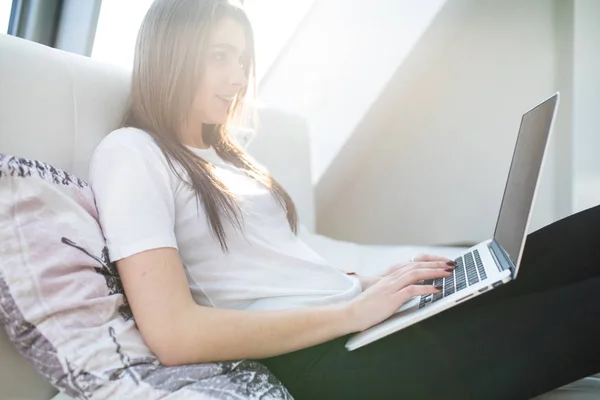 Jeune femme heureuse avec ordinateur portable couché sur le lit — Photo