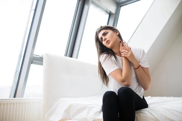 Frau sitzt mit Schmerzen im Nacken auf dem Bett — Stockfoto