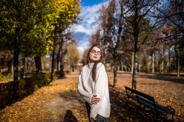 Девушка, гуляющая в ветреном осеннем парке над голубым небом — стоковое фото