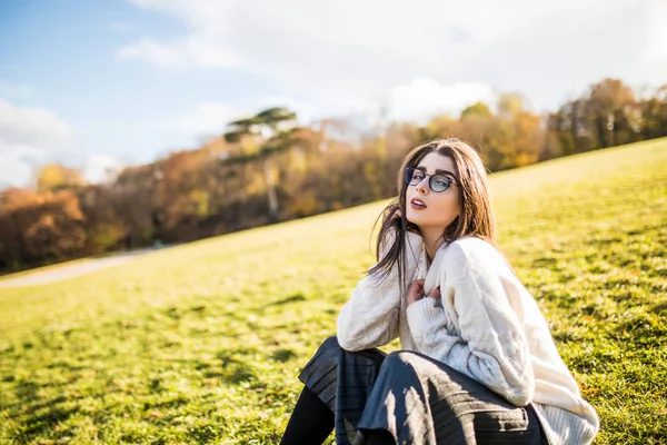 Жінка сидить на траві в парку в сонячний день — стокове фото