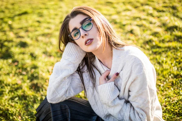 Güneşli günde Park çimenlerin üzerinde oturan kadın