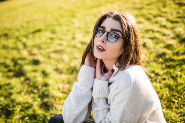 Güneşli günde Park çimenlerin üzerinde oturan kadın