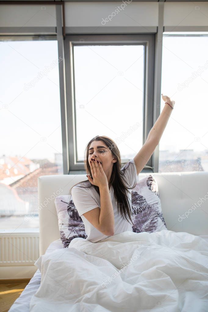Woman stretching and yawing in bed after wake up