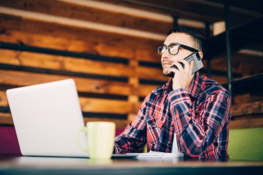 Dizüstü bilgisayar ve ofis telefonda konuşurken masadaki adam