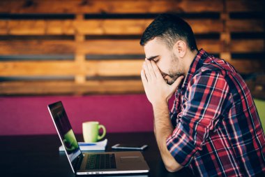 masada dizüstü bilgisayarda bekleyen yorgun genç adam