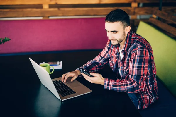 Mann im roten Hemd sitzt am Tisch mit Laptop und Siegesgefühlen im Amt. Coworking — Stockfoto