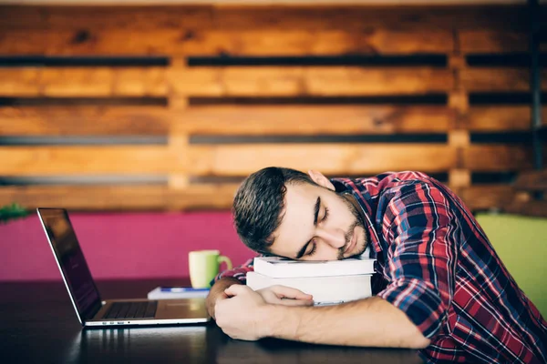 Sleep at work. Young man over tired at work and asleep on books.