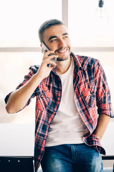 Genç yakışıklı adam konuşmak telefon Office yakınındaki büyük pencereler. — Stok fotoğraf