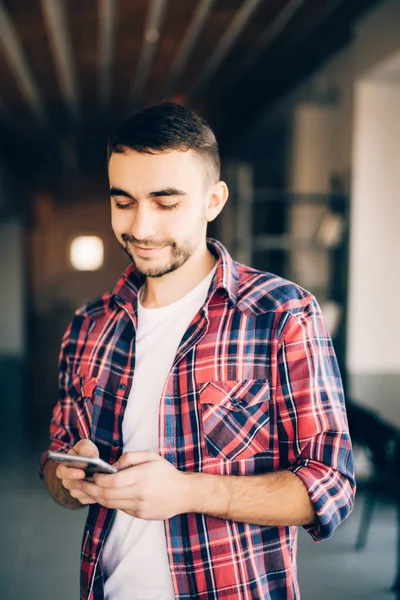 Junger Mann schreibt SMS am Telefon im Büro — Stockfoto