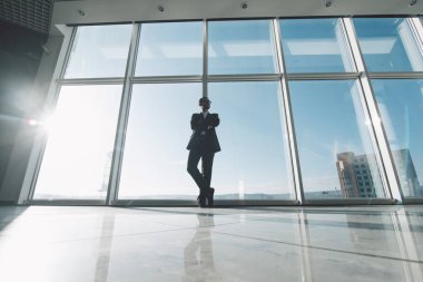 Genç başarı iş adamı panoramik pencerelere karşı