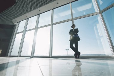 Genç başarı iş adamı panoramik pencerelere karşı