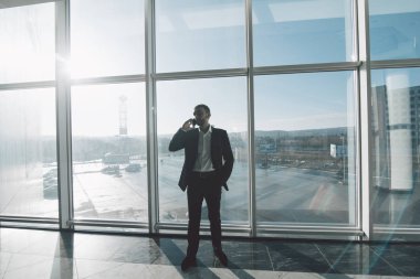 İş adamı konuşmak telefon panoramik pencerelere karşı