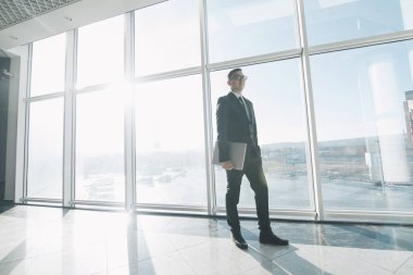 Takım elbise ve gözlük yakışıklı işadamı hareket elinde ofiste dizüstü bilgisayar ile