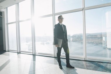 Takım elbise ve gözlük yakışıklı işadamı hareket elinde ofiste dizüstü bilgisayar ile