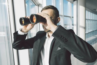 İş adamı dürbün ile panoramik pencerelere üzerinde seyir