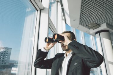 İş adamı dürbün ile panoramik pencerelere üzerinde seyir