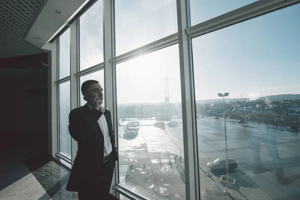 Homme d'affaires parler téléphone contre les fenêtres panoramiques — Photo