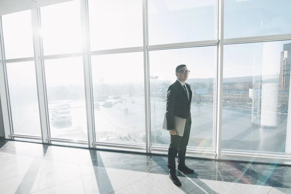 Beau homme d'affaires en costume et lunettes se déplacent avec ordinateur portable dans les mains au bureau — Photo