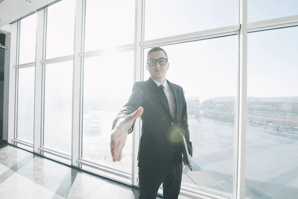 Przystojny biznesmen w garnitur i okulary dają uzgadniania w pomieszczenie biurowe z panoramicznymi oknami — Zdjęcie stockowe