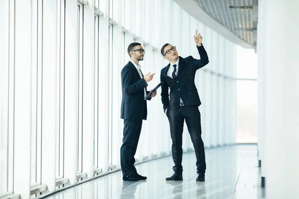 Deux hommes d'affaires dictant le changement de bâtiment dans une grande salle panoramique — Photo