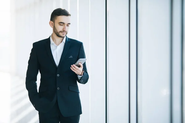Pohledný podnikatel v obleku přečíst sms na telefonu v terminálu — Stock fotografie