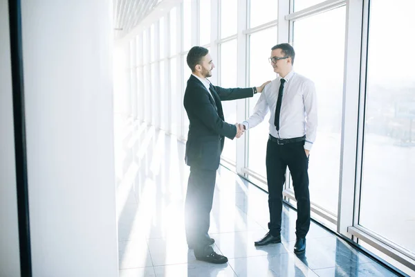 Deux hommes d'affaires serrant la main au bureau avec des fenêtres panoramiques — Photo