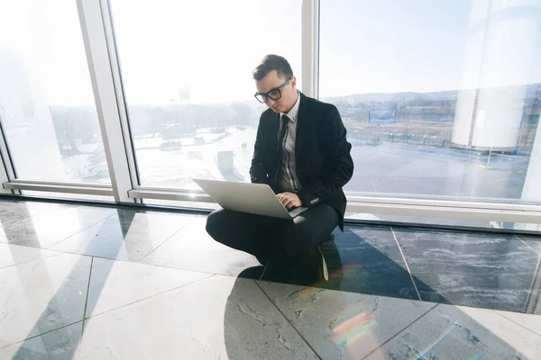Homme d'affaires sur le sol avec ordinateur portable dans les fenêtres panoramiques — Photo