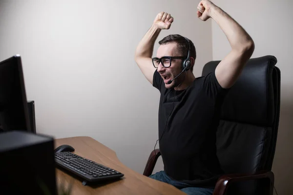 Giovane giocatore in cuffie e occhiali utilizzando il computer per giocare — Foto Stock