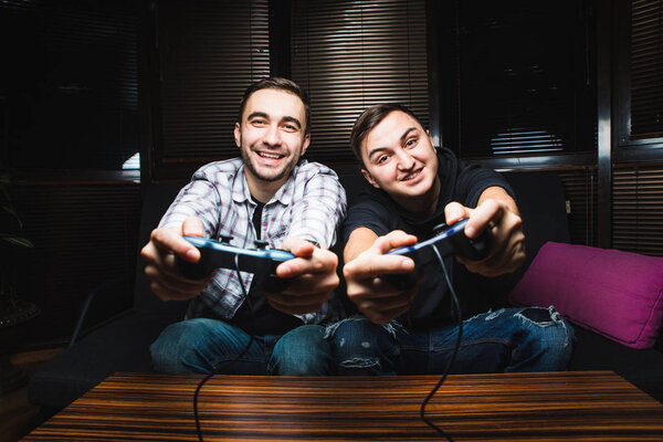 Two young happy men playing video games