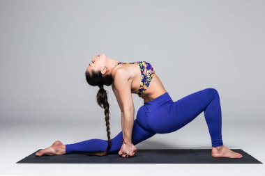 Güzel yoga kadın pratik yoga gri arka plan üzerinde teşkil etmektedir..