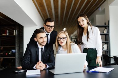 Takım toplantısı. Takım proje ofis içinde laptop üzerinde izlerken.