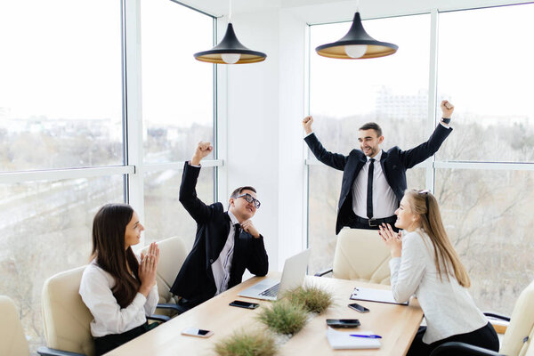Деловая встреча Деловые люди в формальной одежде празднуют победу, сидя за столом
